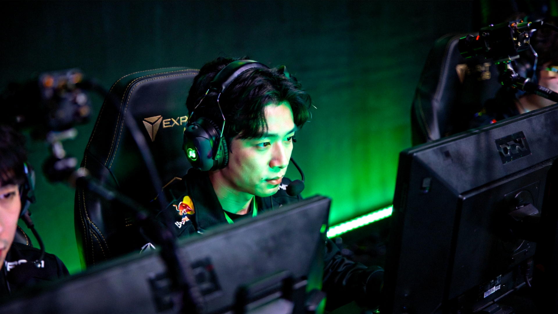 电竞选手在昏暗灯光下专注比赛，屏幕发出绿色光芒，展现完美电竞平台的沉浸式电竞赛事氛围